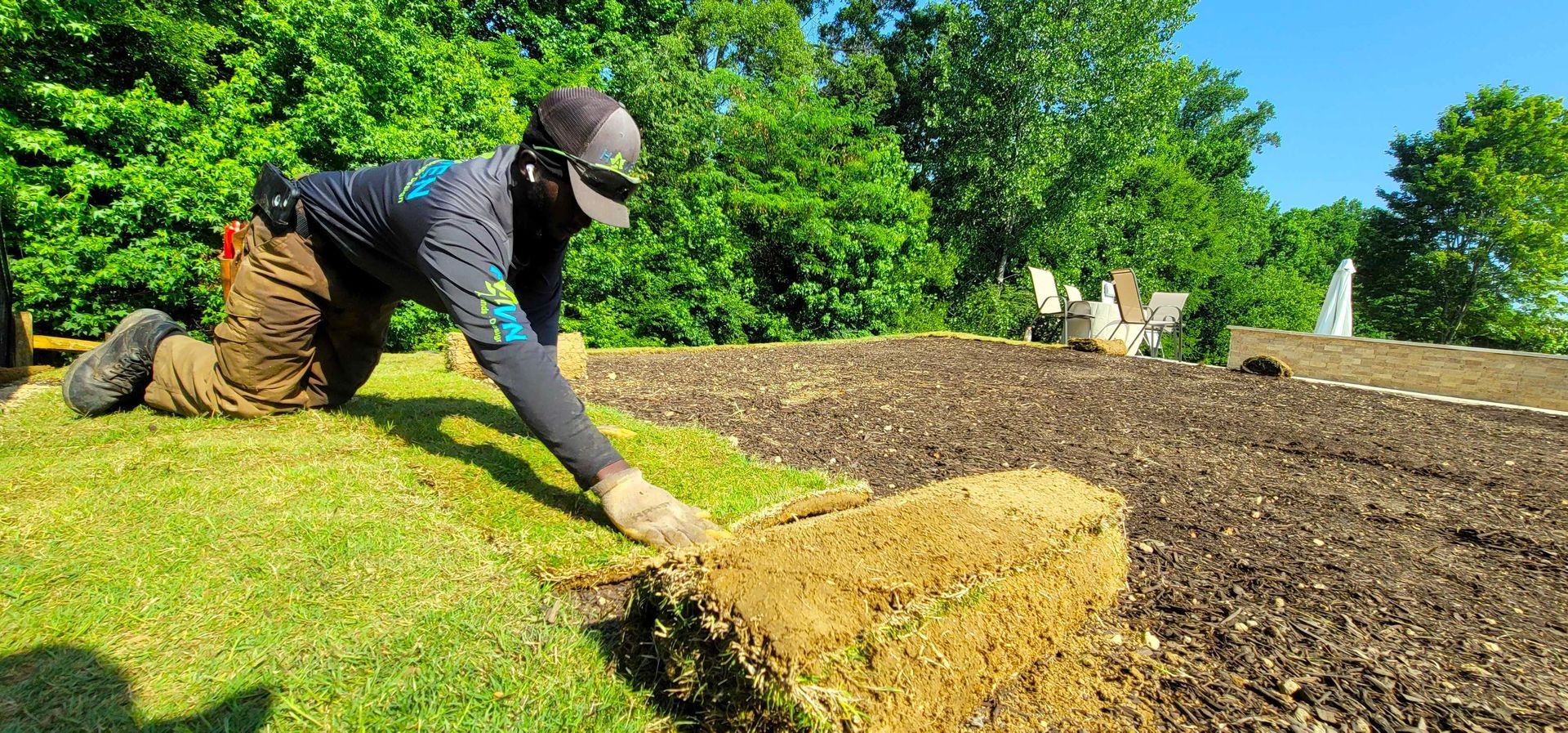 A man is laying grass on top of a pile of dirt.