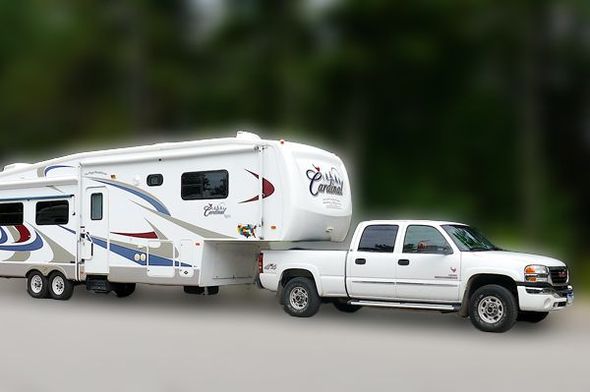 Dual axel camper trailer attached to a white truck.