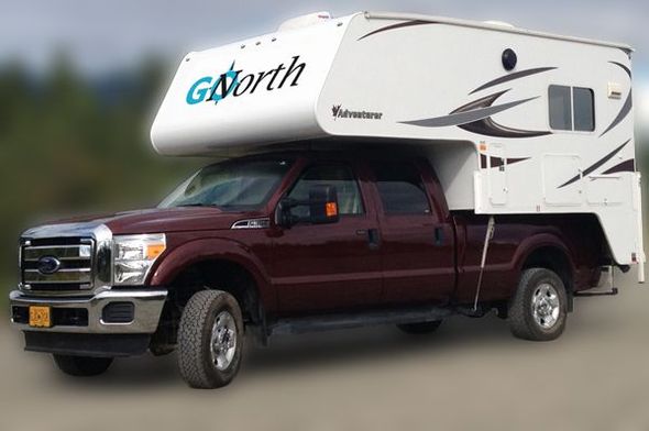A truck camper needing repair by the side of the road.