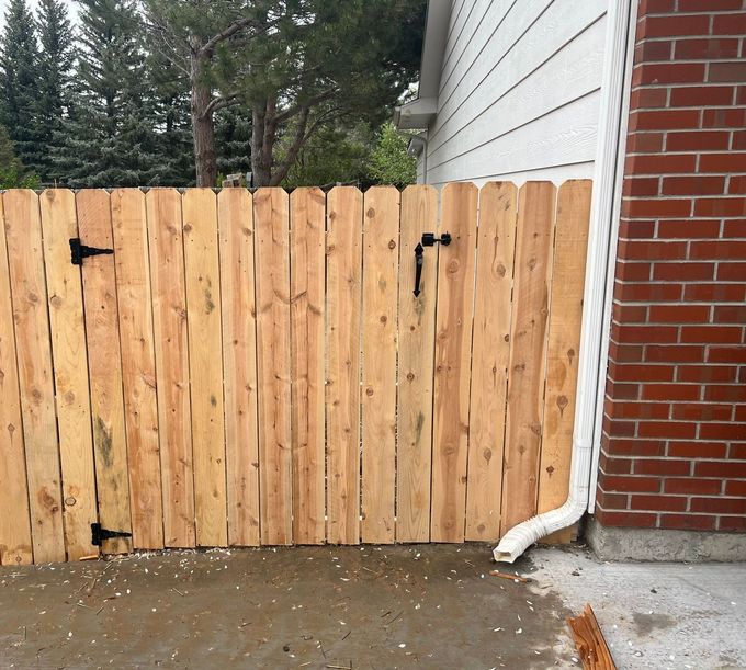 A wooden fence is next to a brick building