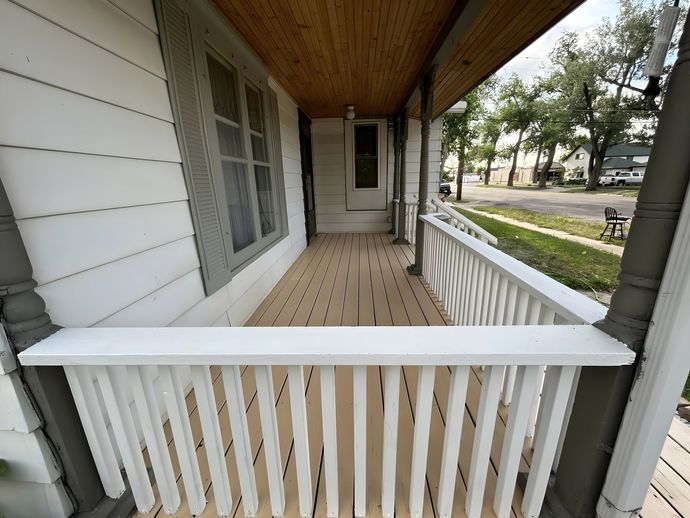 A porch with a white railing and a wooden ceiling