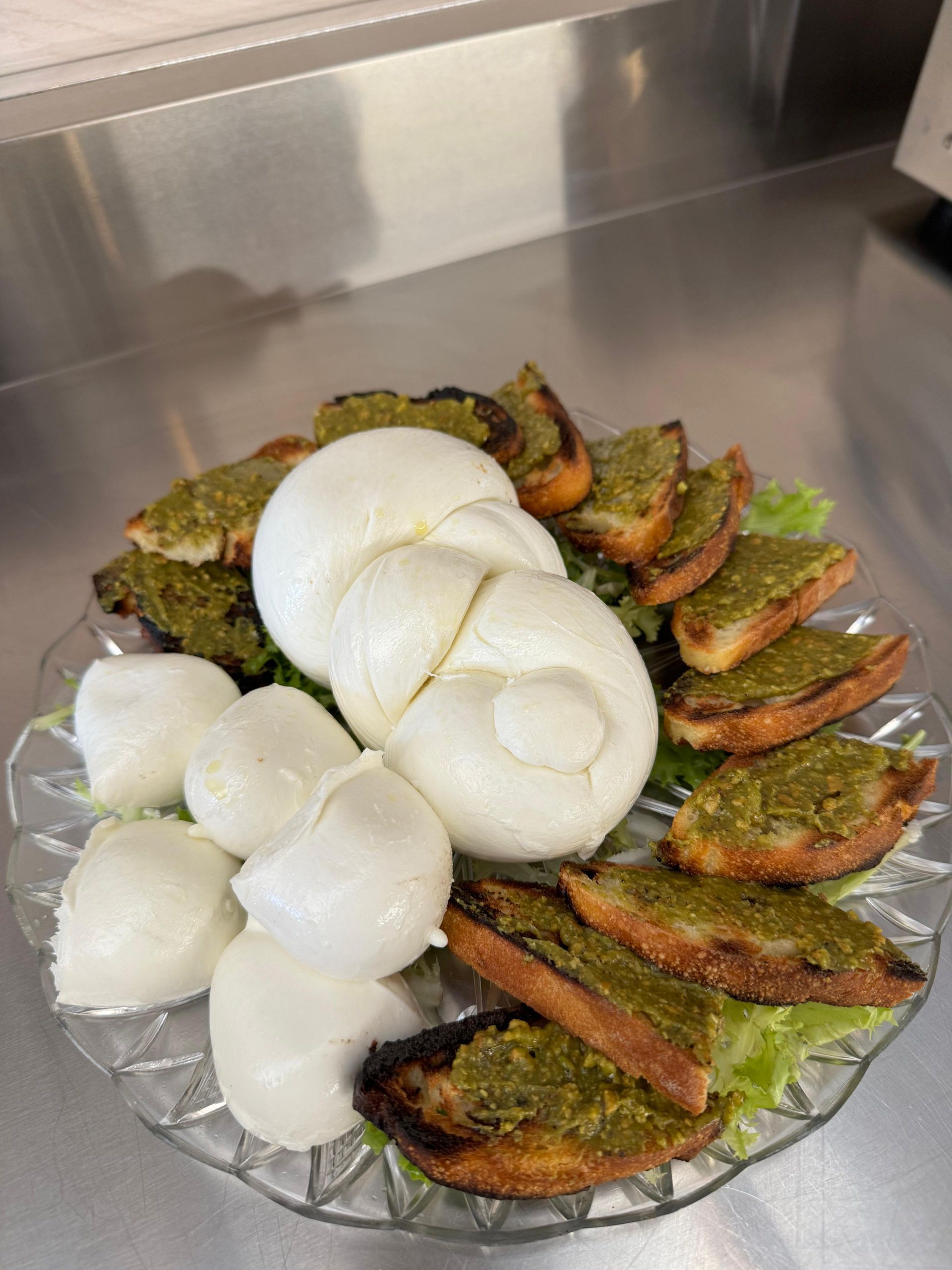 Un piatto di cibo con mozzarella e pesto su un tavolo.