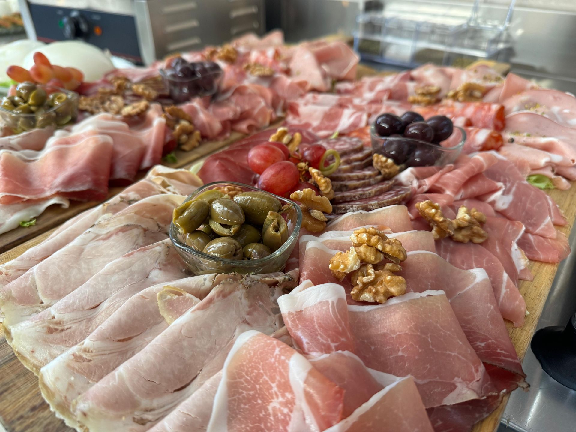 Un tagliere di legno sul quale vengono disposti vari tipi di carne e verdure.