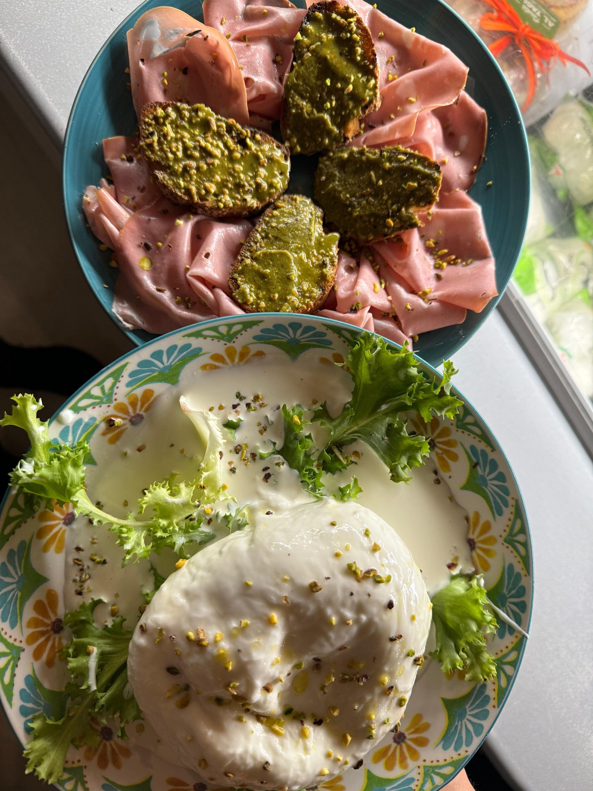 Due piatti di cibo sono su un tavolo, tra cui un piatto di carne e un piatto di formaggio