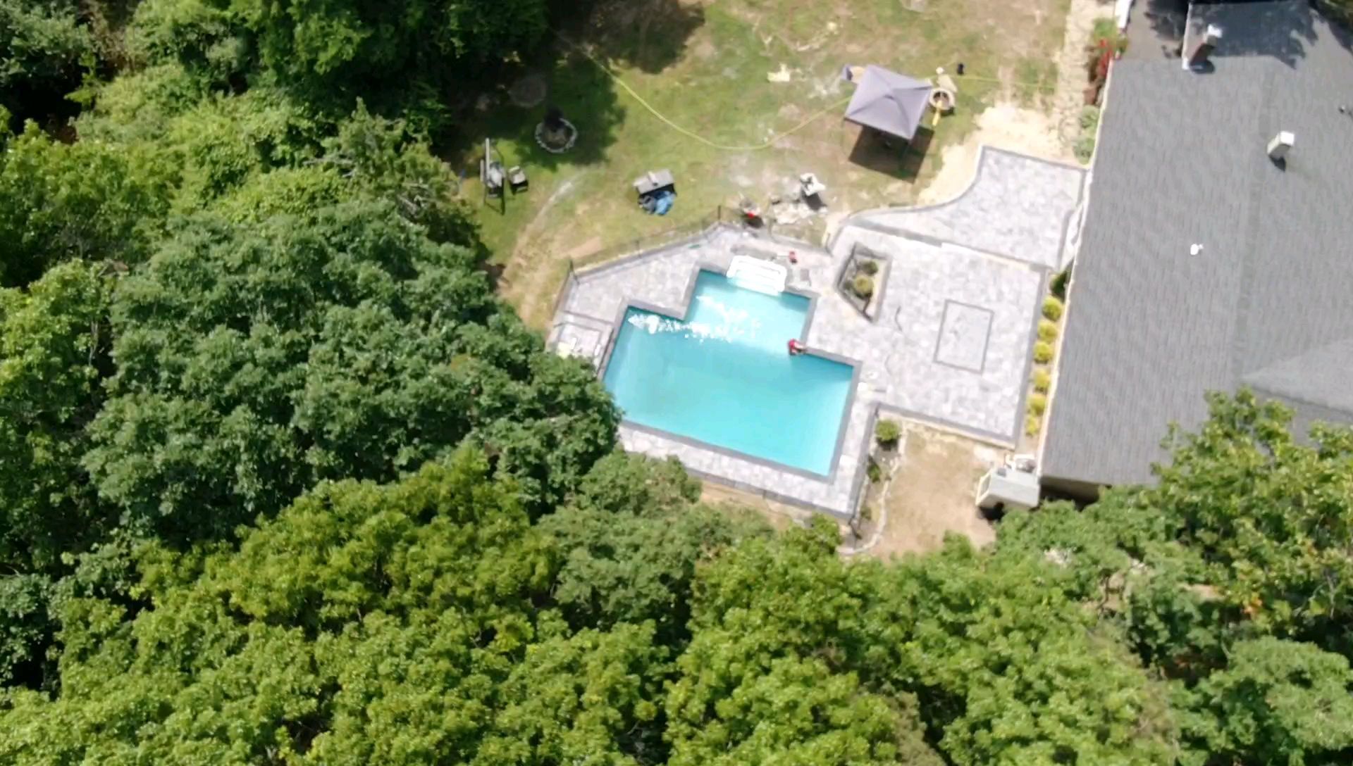 An aerial view of a swimming pool in a backyard surrounded by trees.
