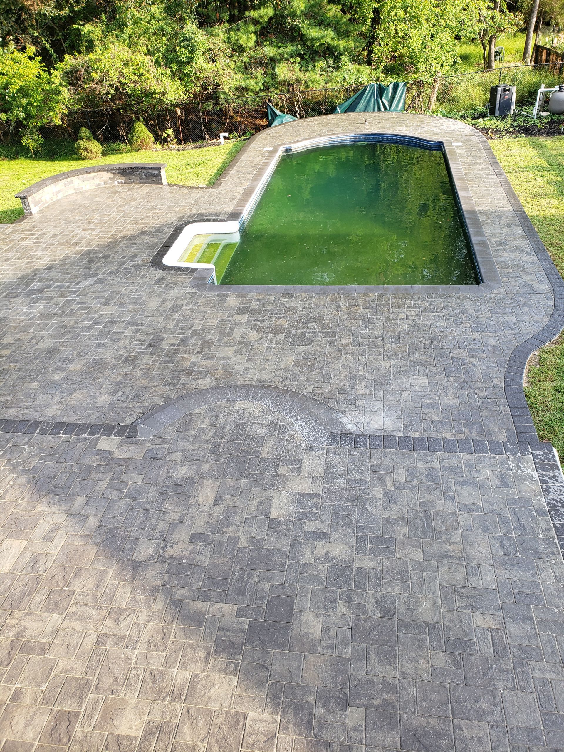 There is a swimming pool in the middle of a patio.