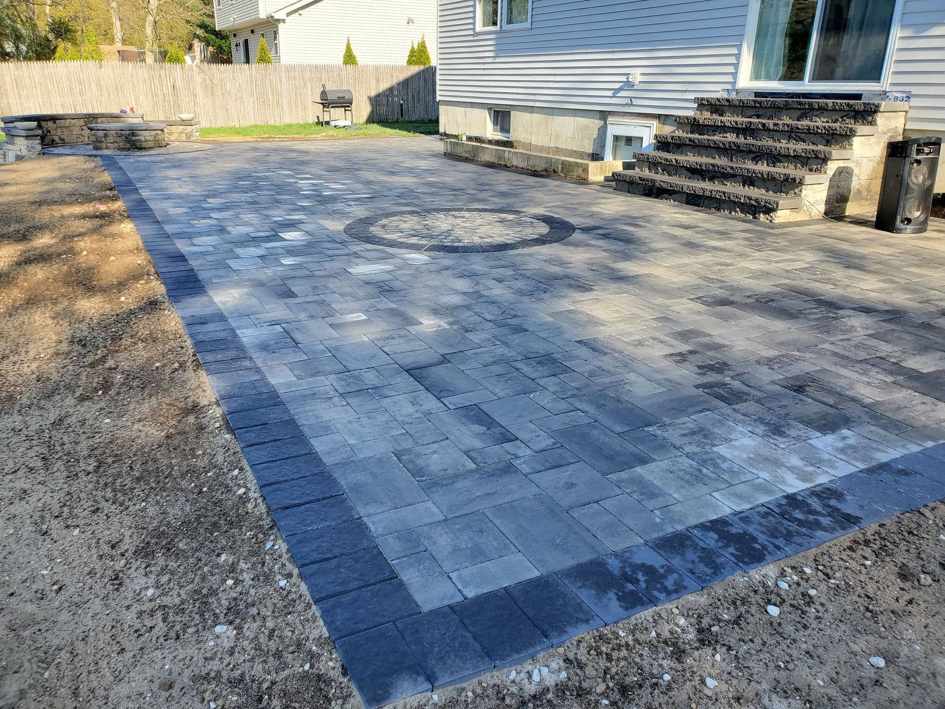 A patio with stairs and a fire pit in front of a house.