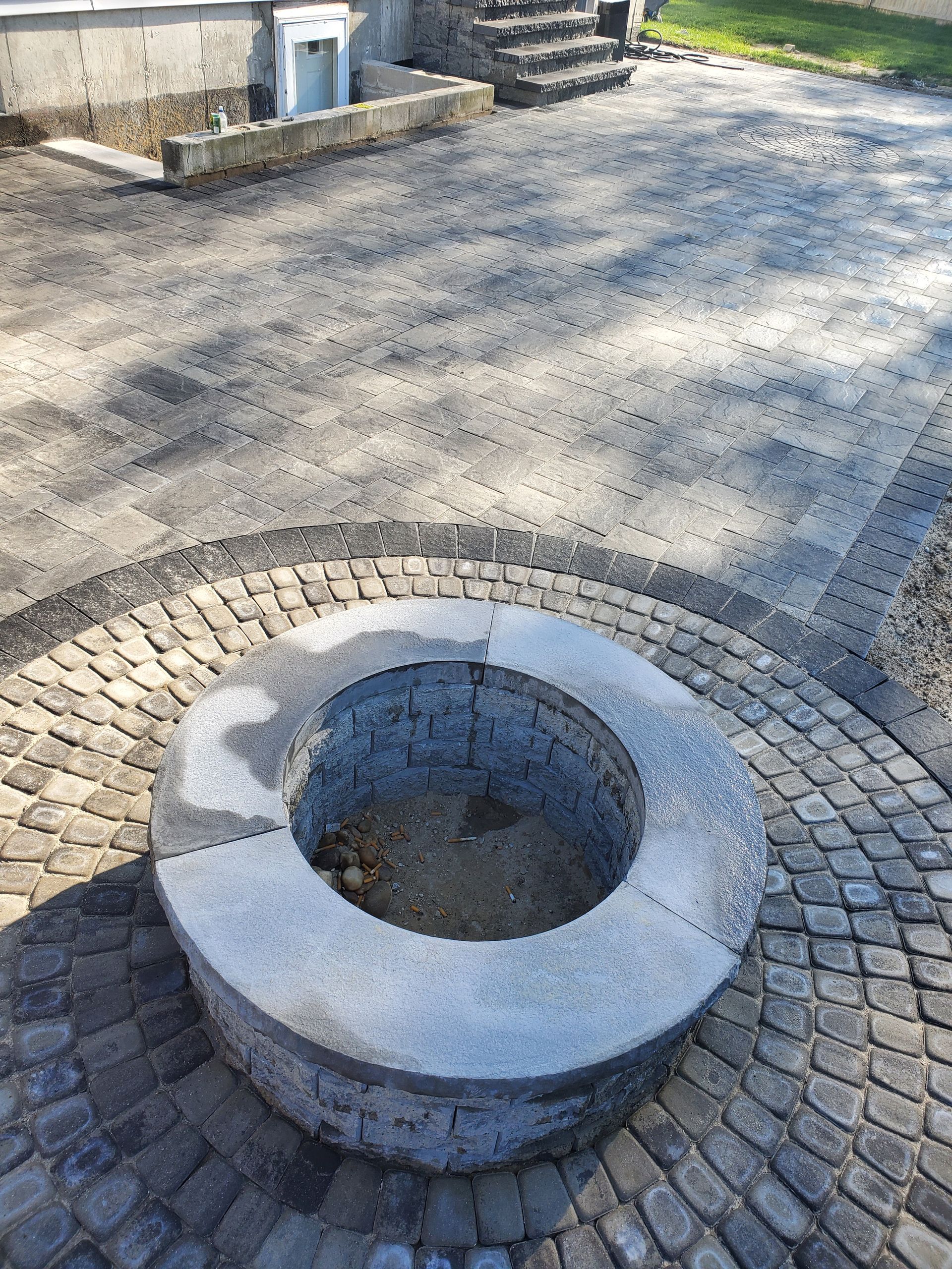 A fire pit is sitting on top of a brick patio.