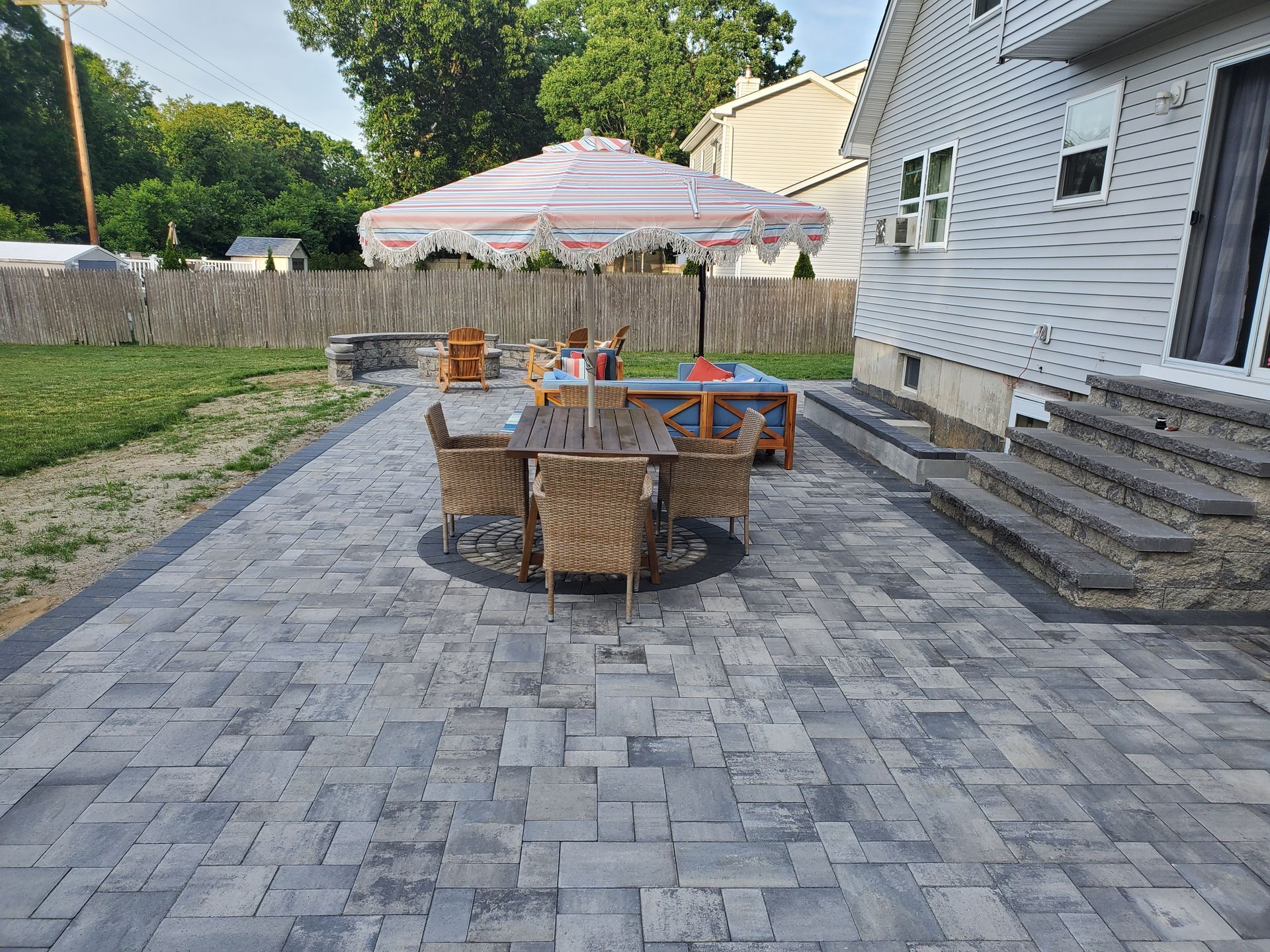 A patio with a table and chairs and an umbrella in front of a house.