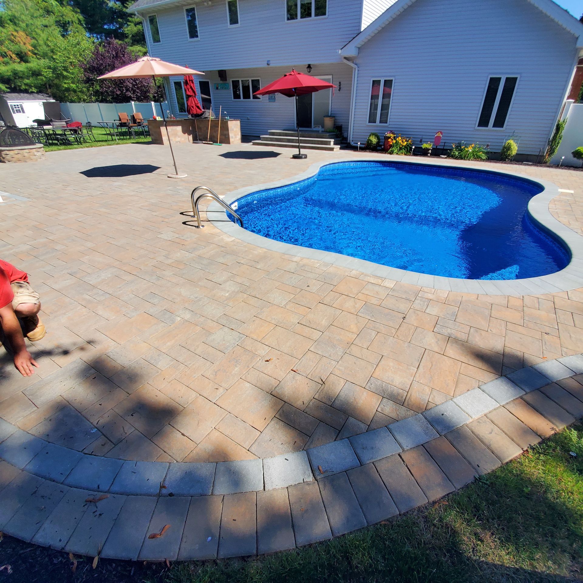 A large swimming pool is surrounded by a brick patio