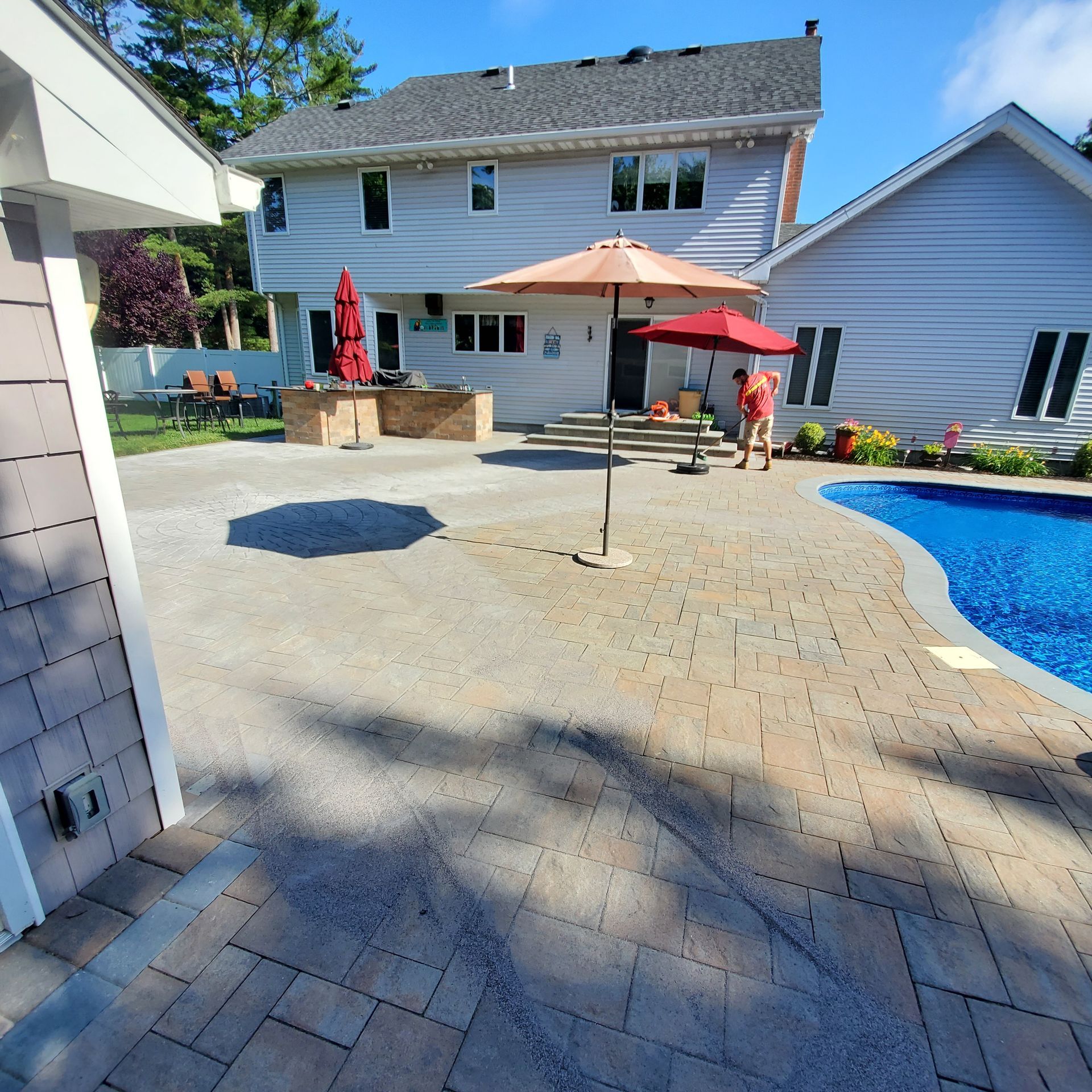 A patio with umbrellas and a pool in front of a house
