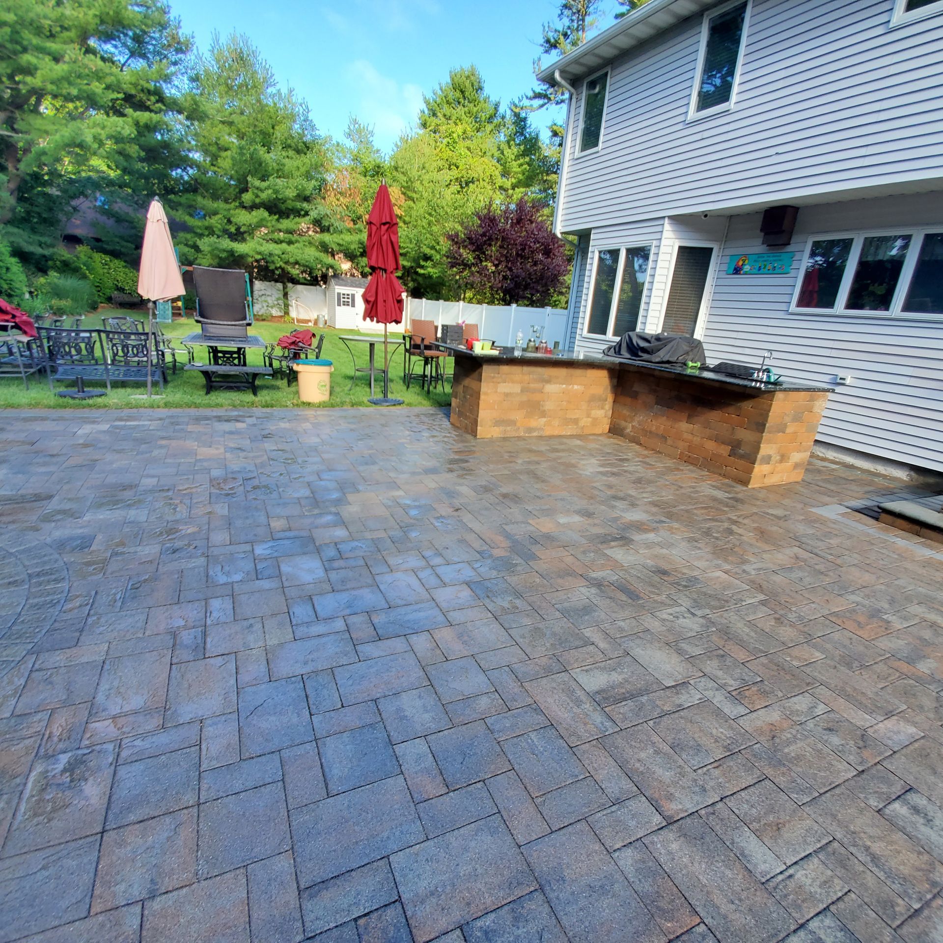 A brick patio with a table and chairs in front of a house
