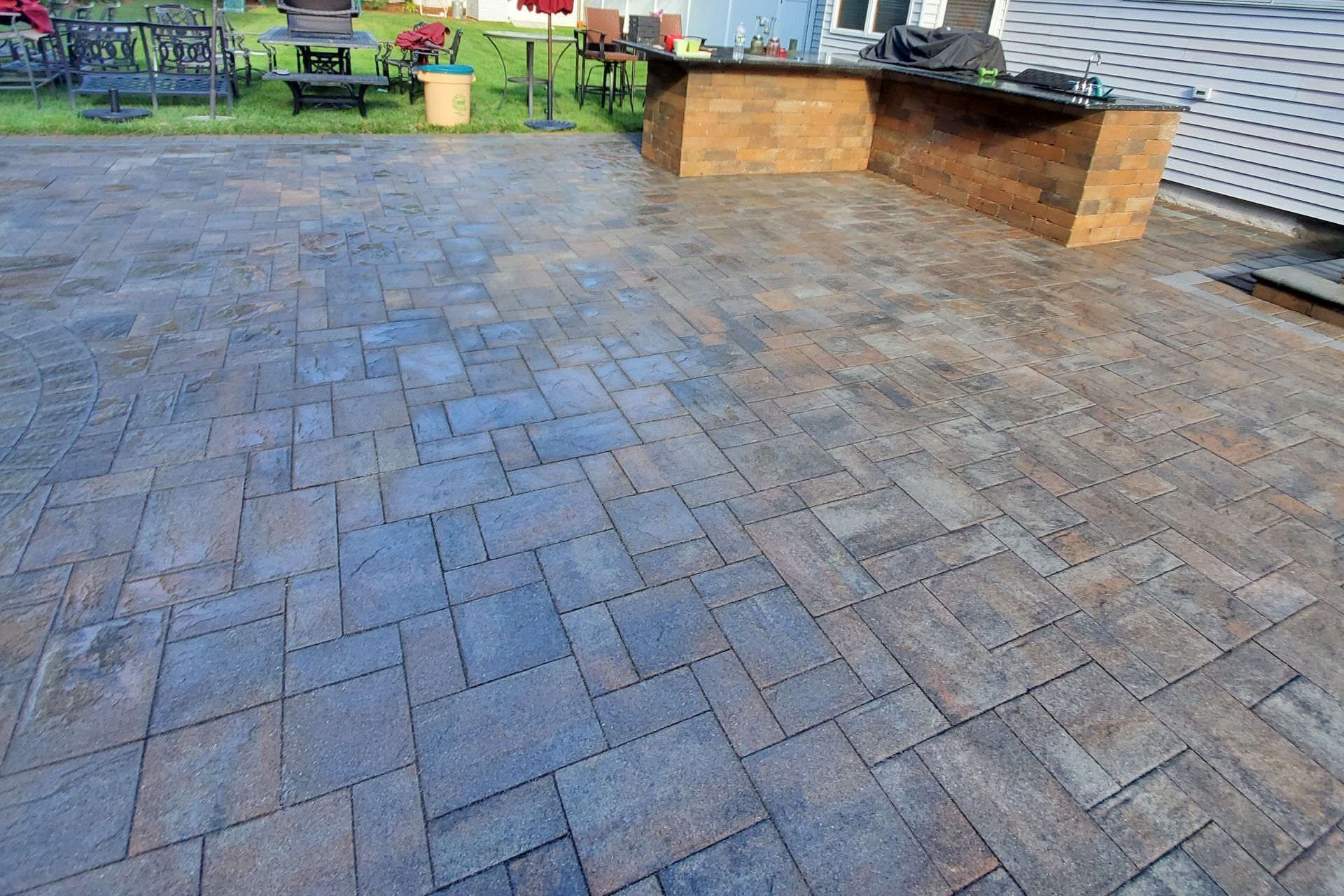 A brick patio with a wooden table and chairs in the background.
