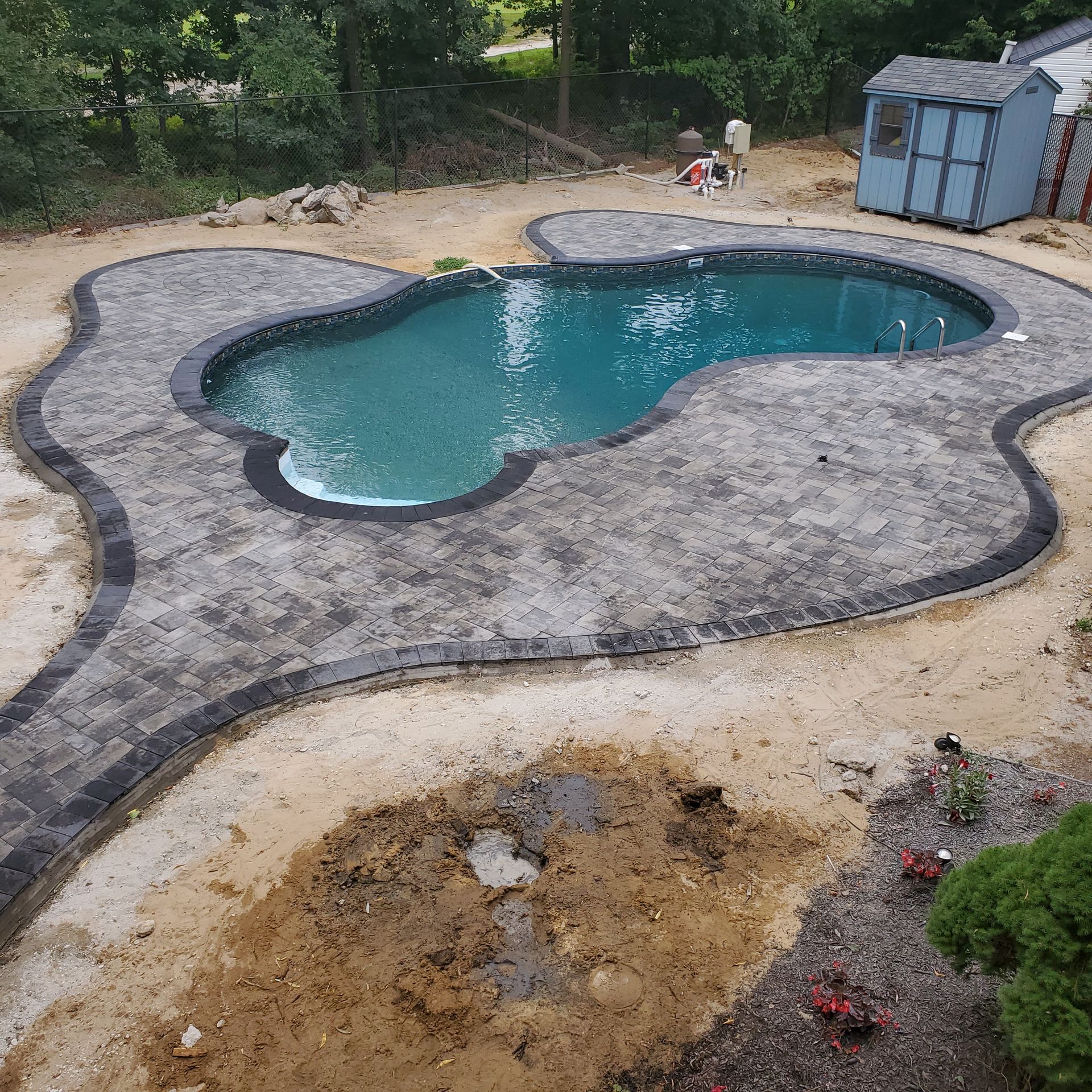 An aerial view of a swimming pool with a shed in the background