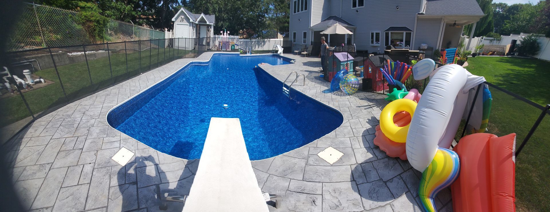 A large swimming pool with a diving board in the backyard.