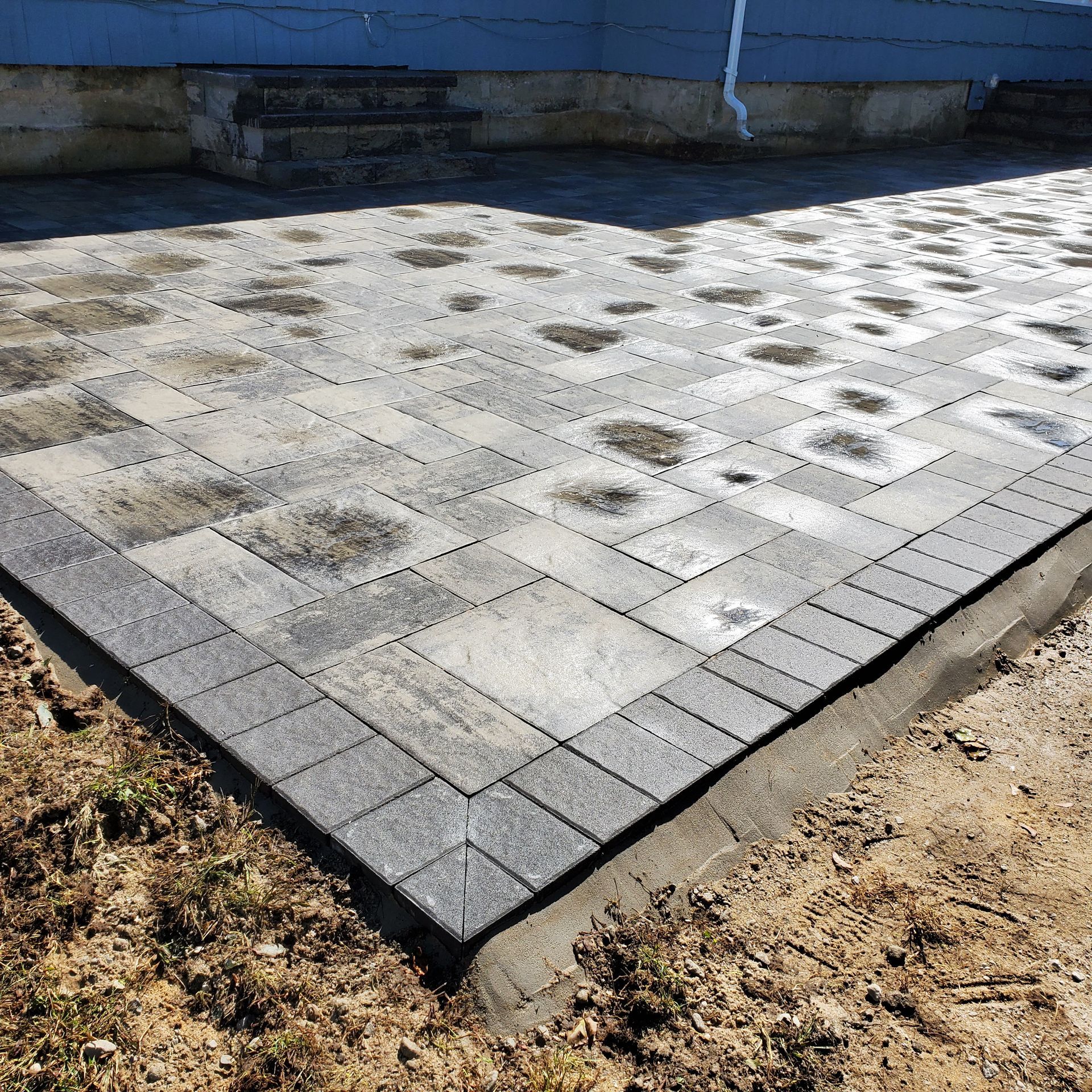 A brick walkway is being built in front of a blue house.