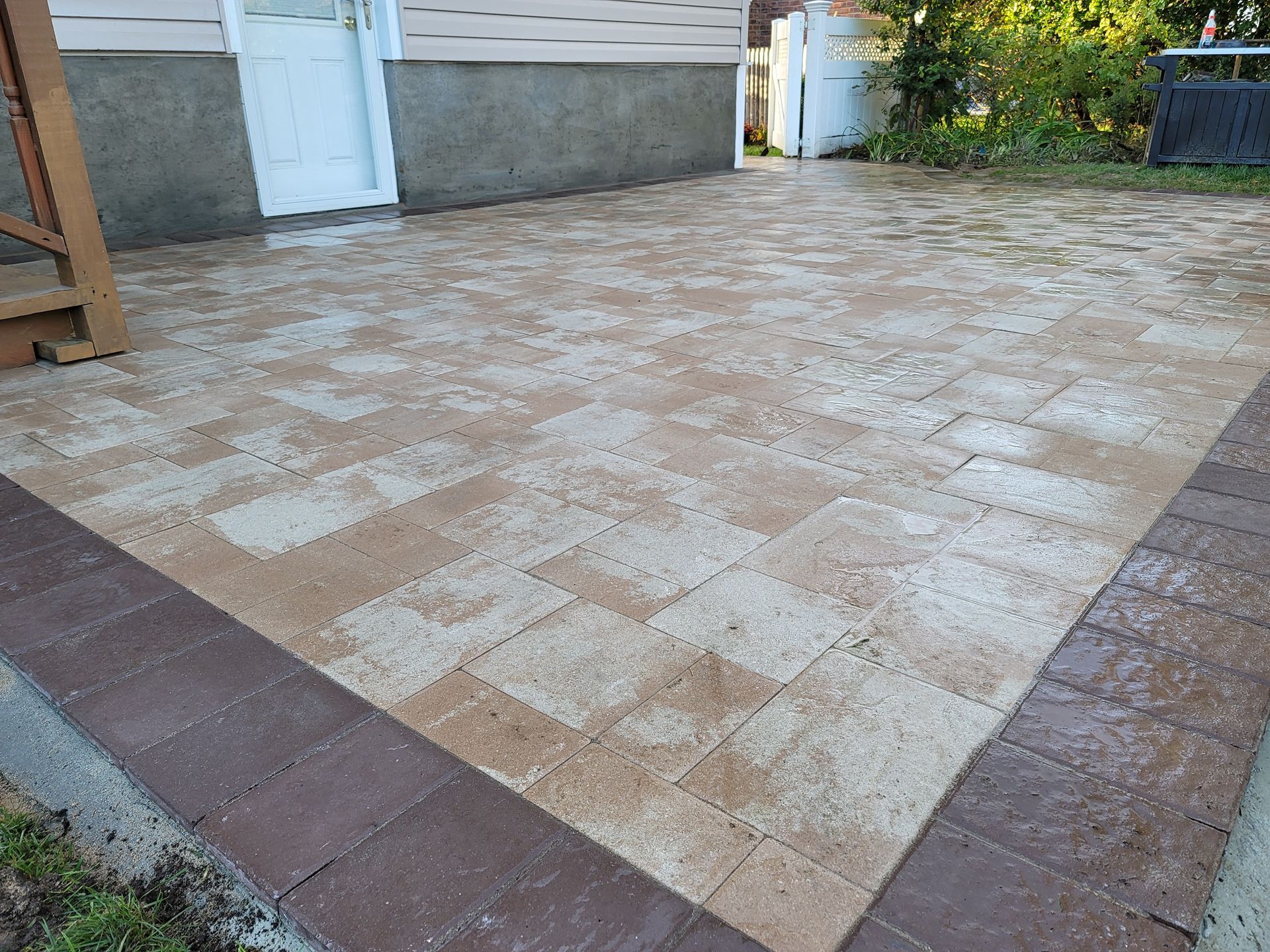 A brick patio with a wooden staircase in front of a house.