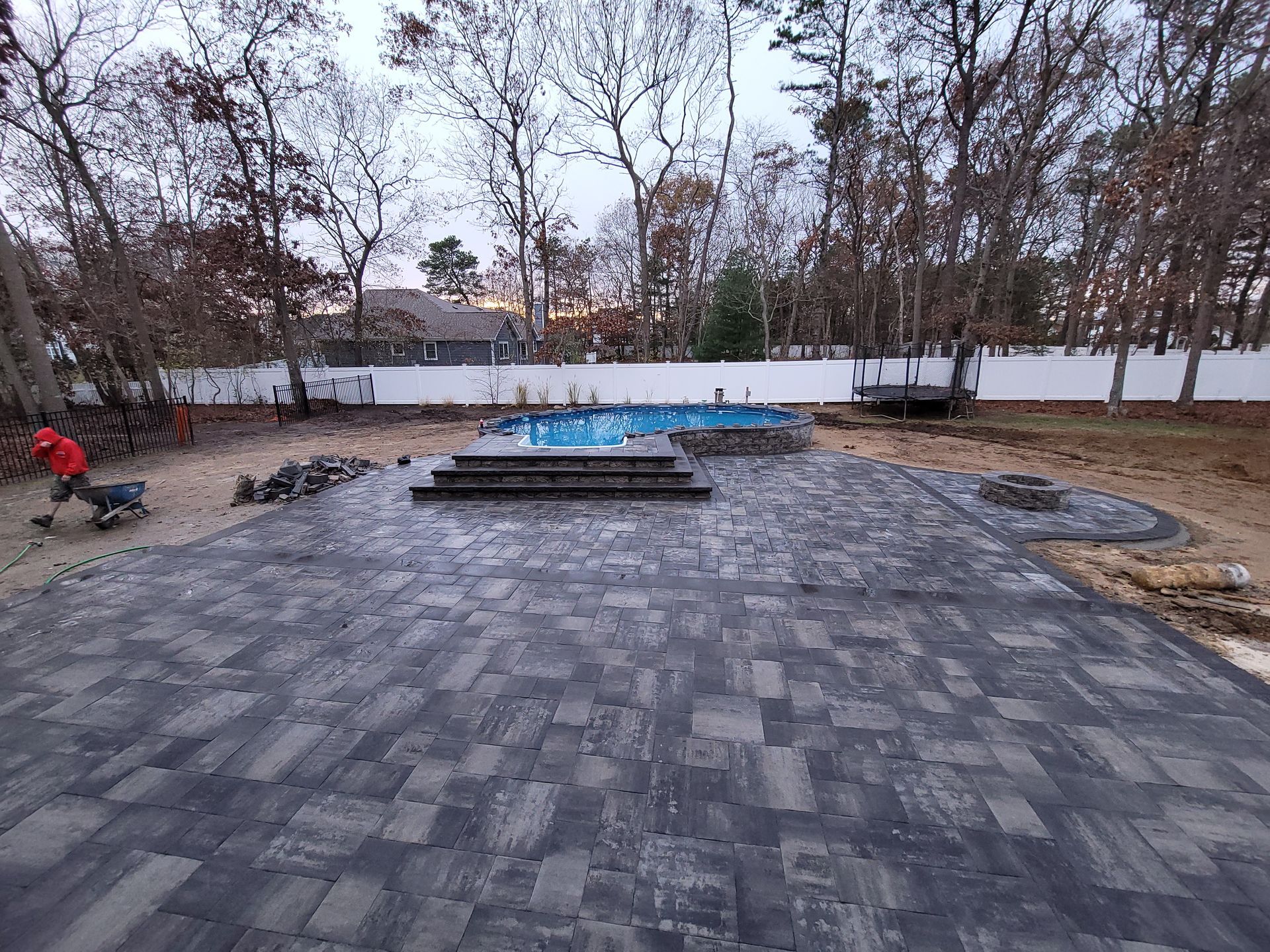 A man is working on a patio next to a pool.