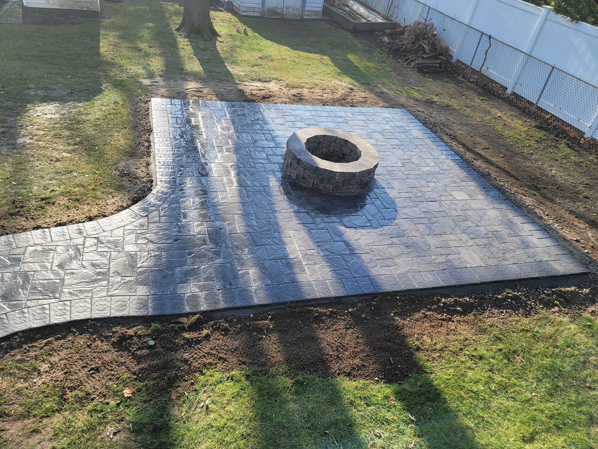 A fire pit is sitting on top of a brick patio in a backyard.
