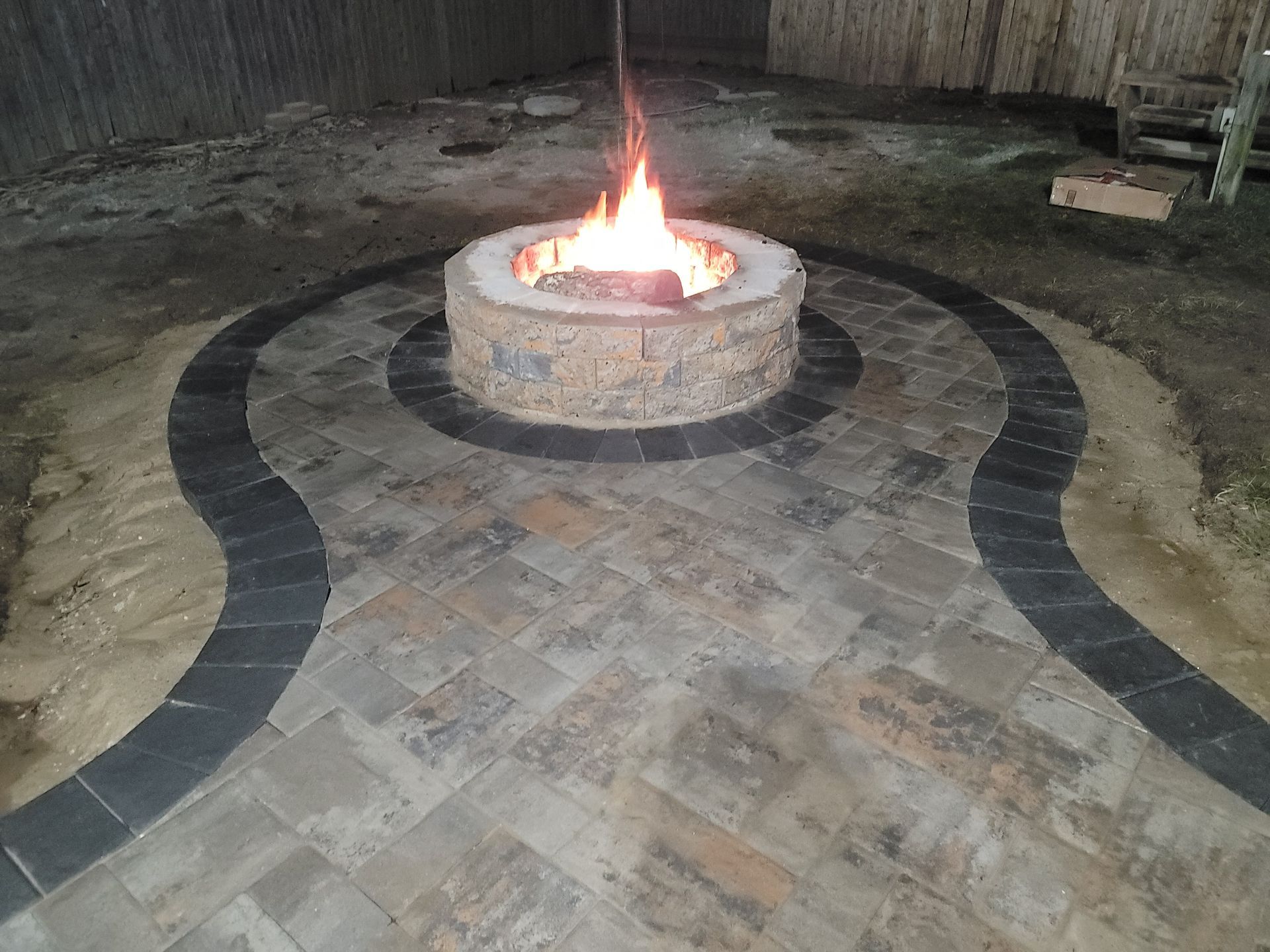 A fire pit is surrounded by bricks on a patio.