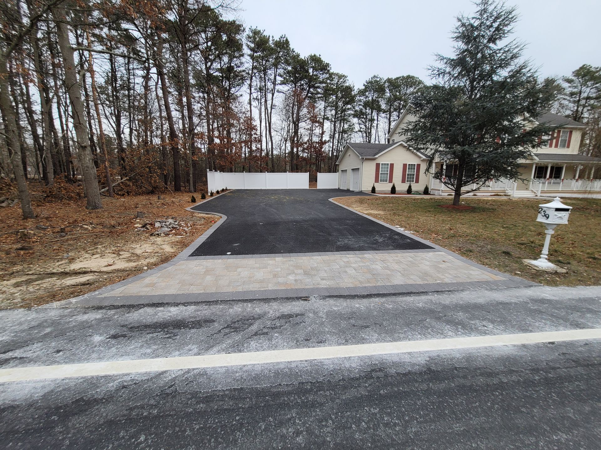 A driveway leading to a house with trees in the background