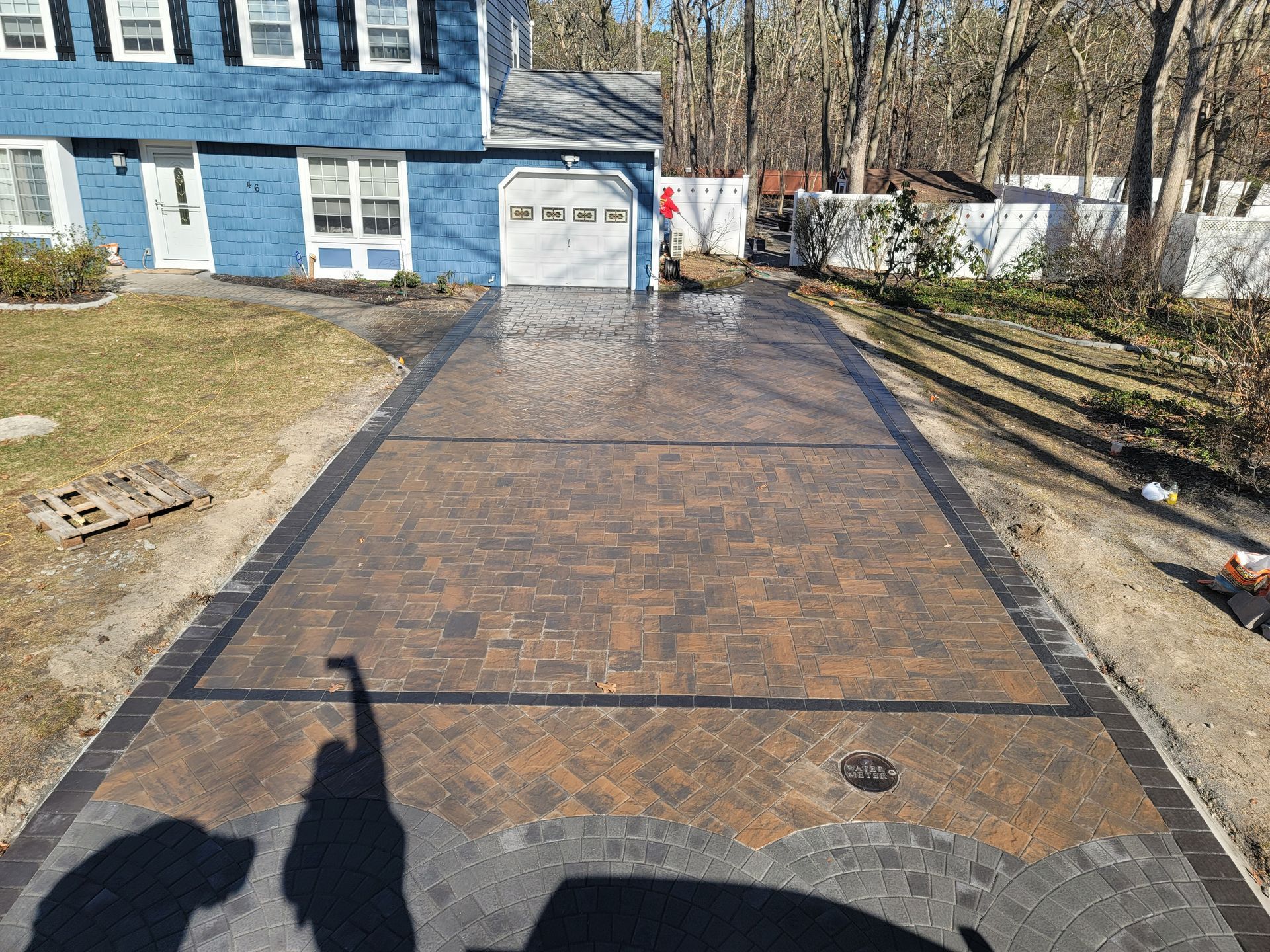 A brick driveway is being built in front of a blue house.