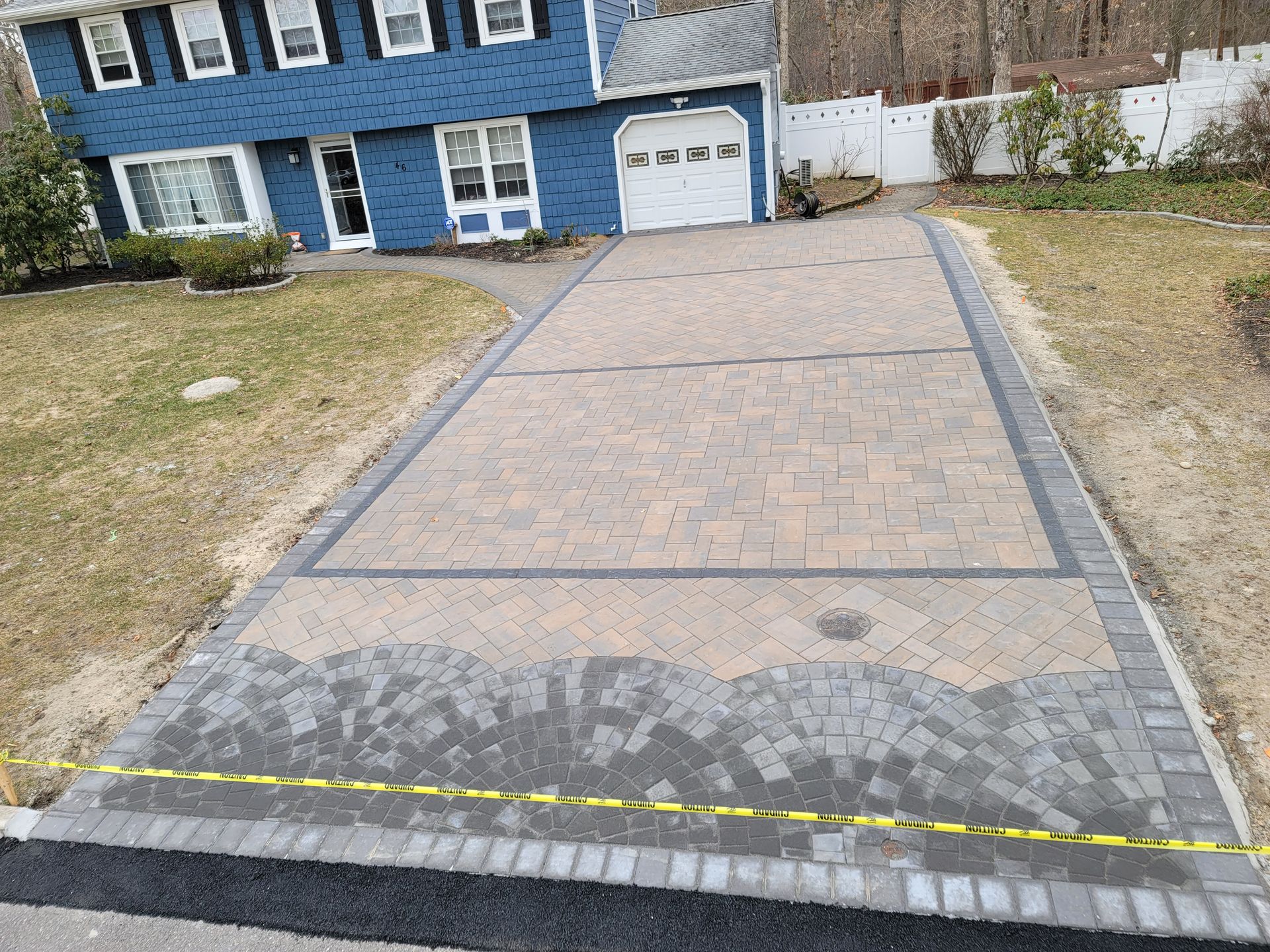 A brick driveway is being built in front of a blue house.