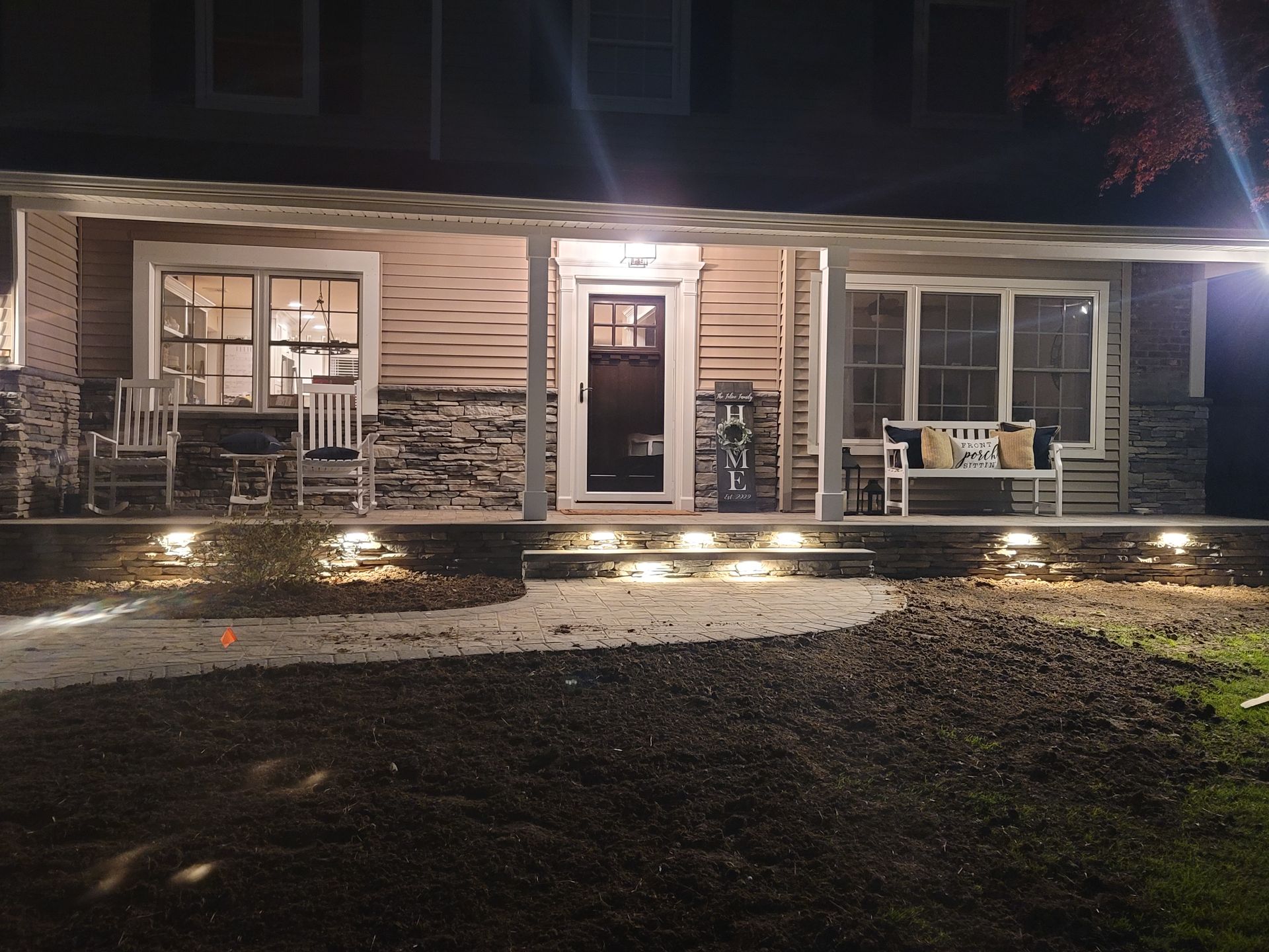 The front porch of a house is lit up at night