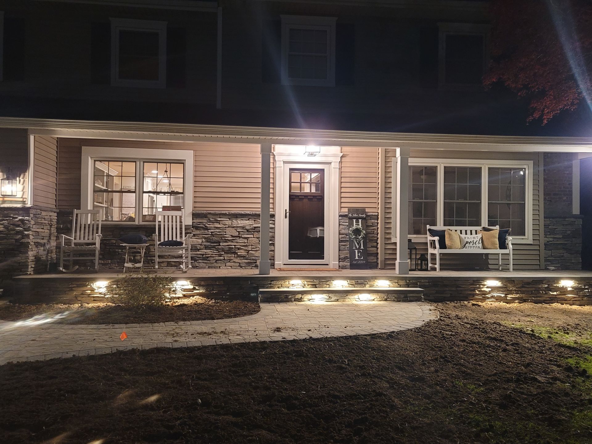 The front porch of a house is lit up at night