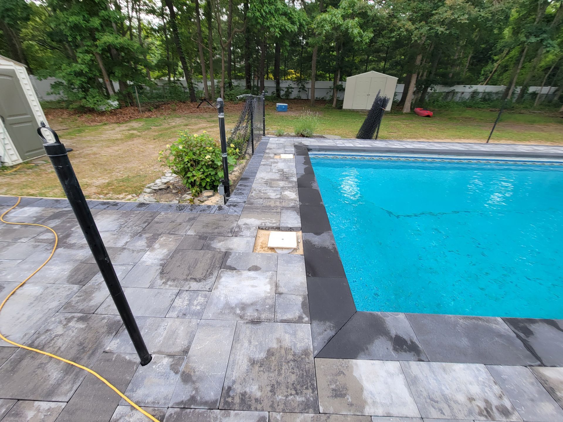 A large swimming pool is surrounded by a patio and trees.