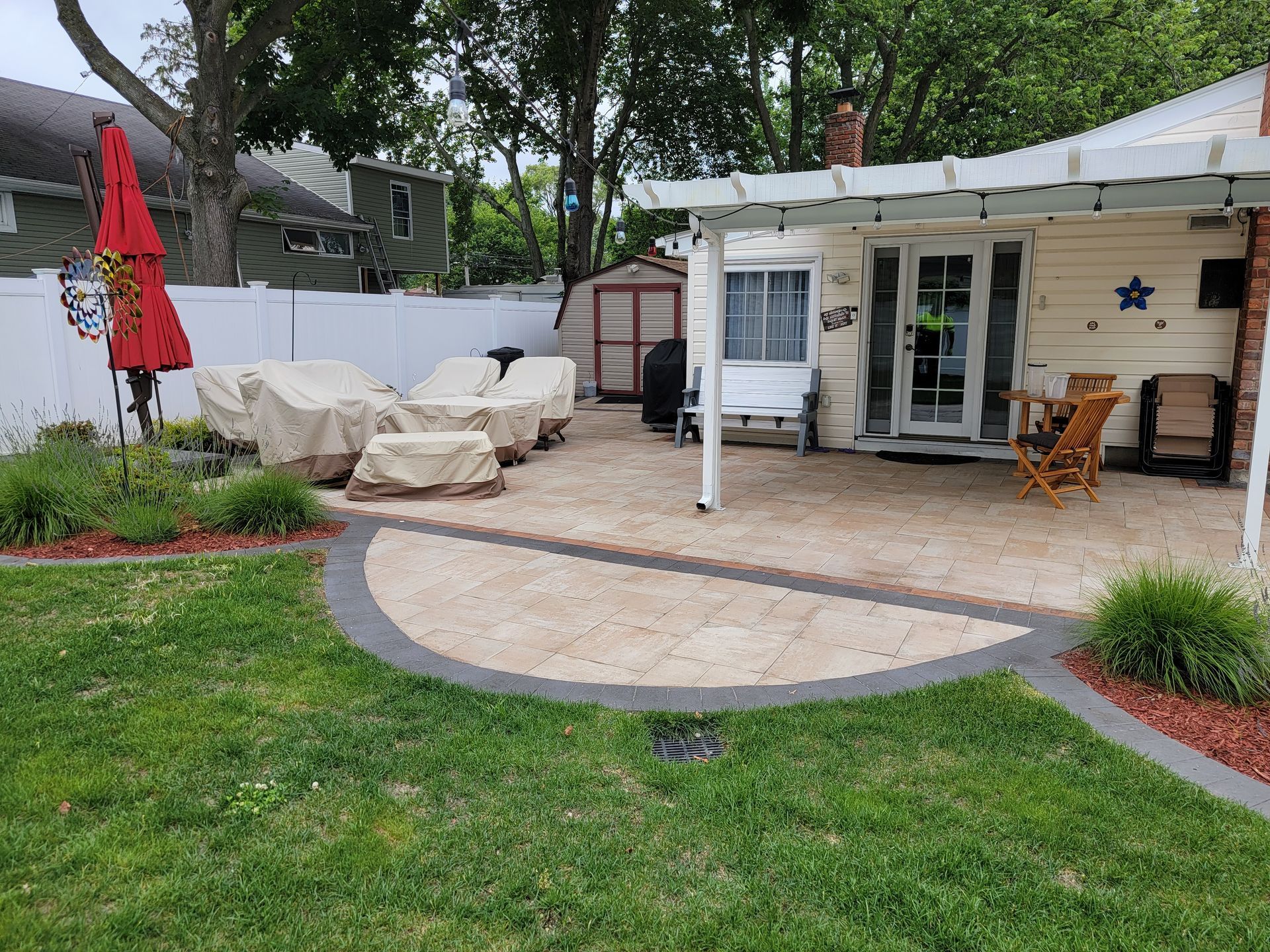 A backyard with a patio and a house in the background.