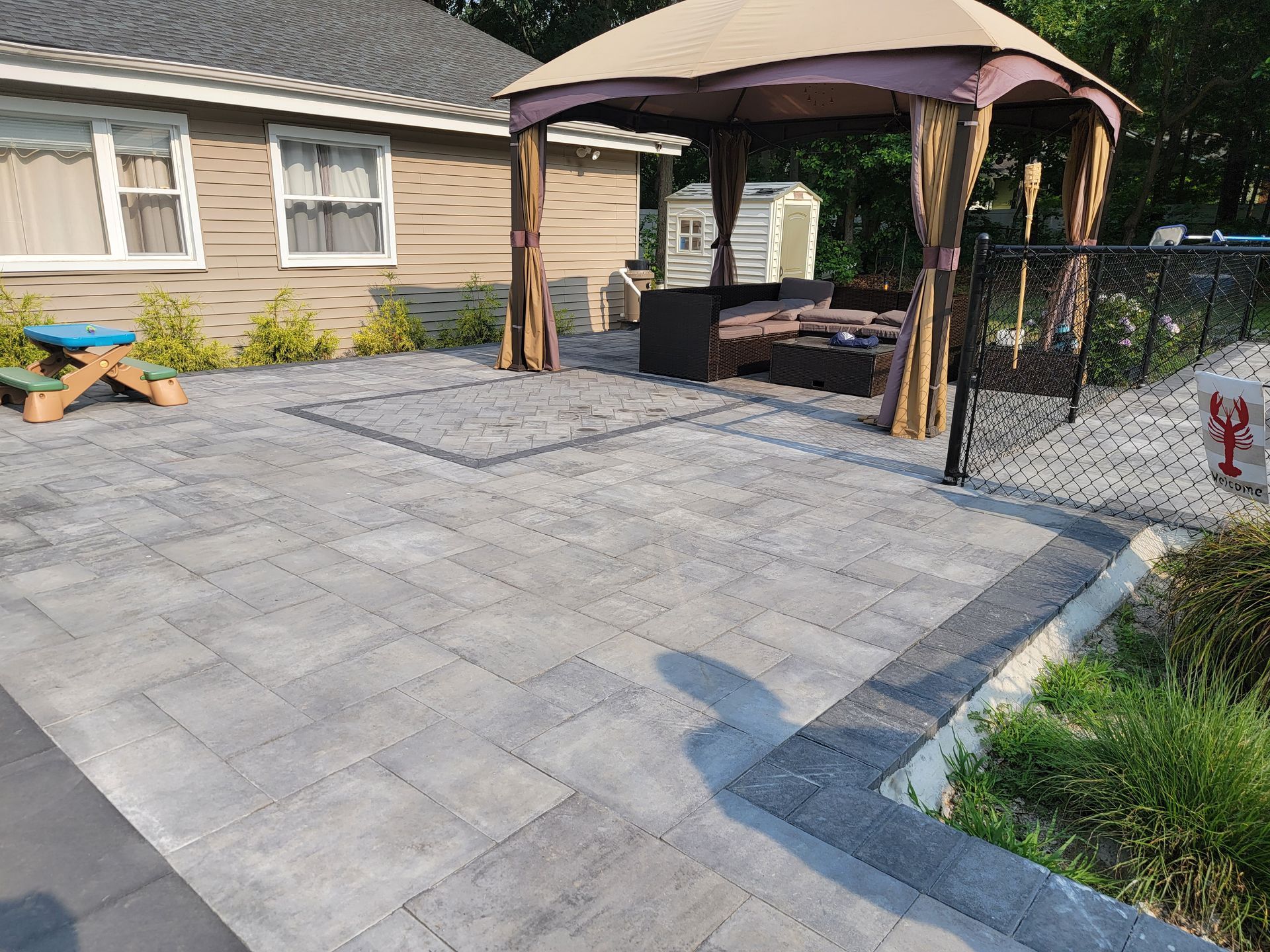 A patio with a gazebo and a picnic table in front of a house.