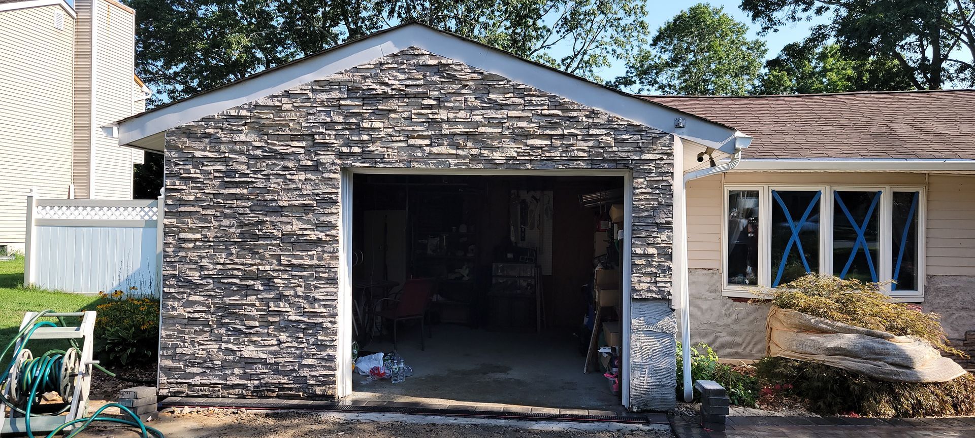 A garage with a stone wall is being built in front of a house.