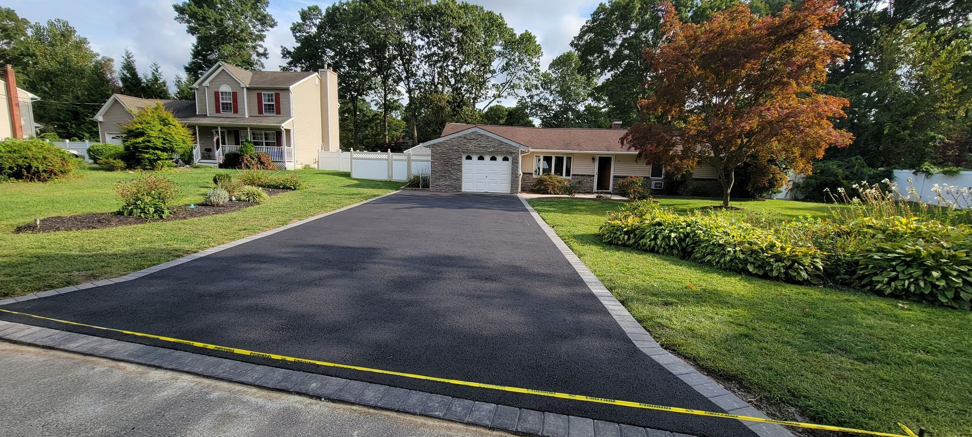 A driveway leading to a house with a lot of grass and trees.