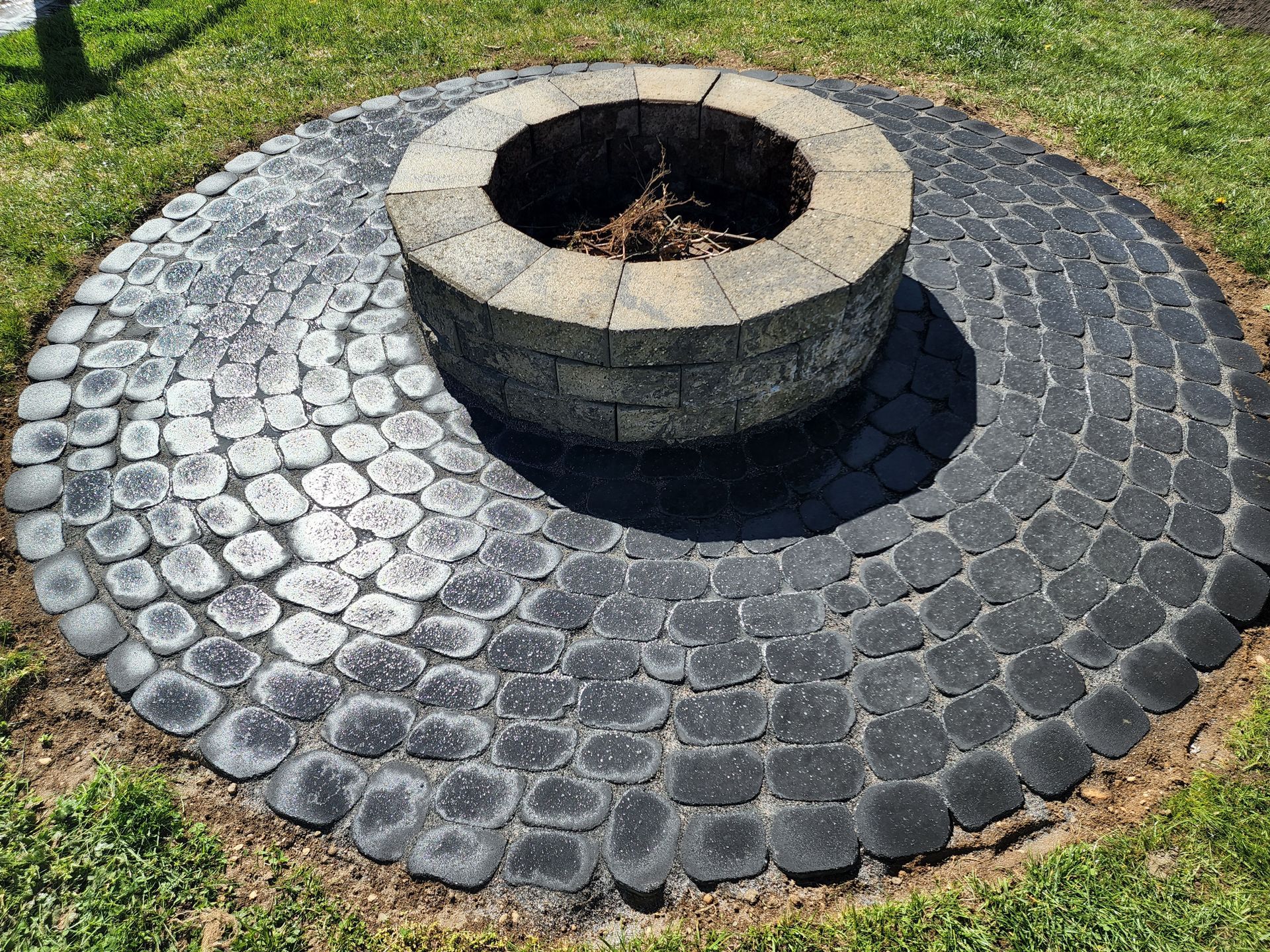 A fire pit is surrounded by a circular brick walkway.