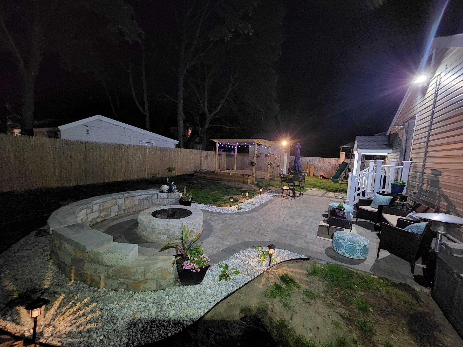 A fire pit in the backyard of a house at night.