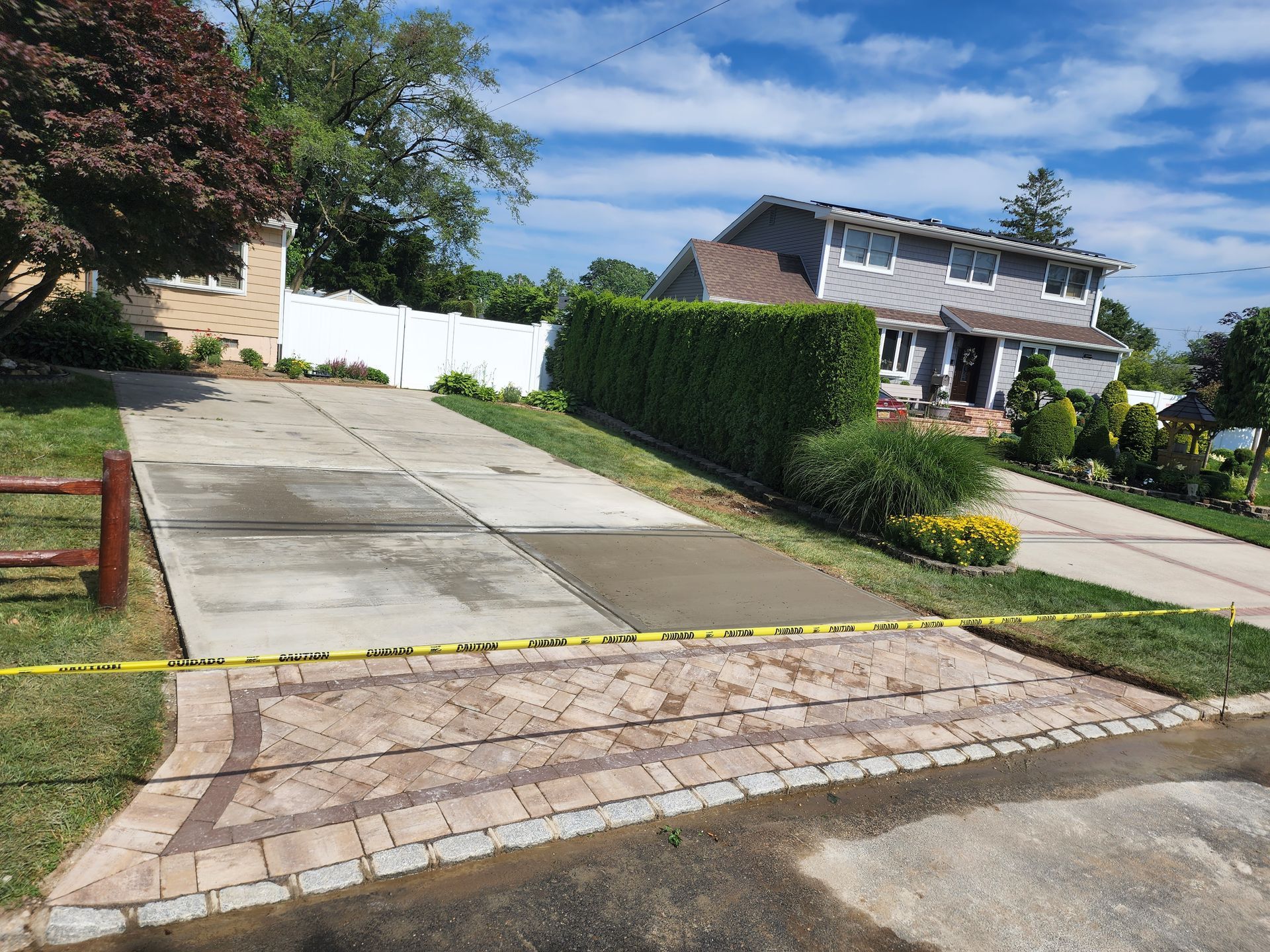 A concrete driveway with a fence and a house in the background