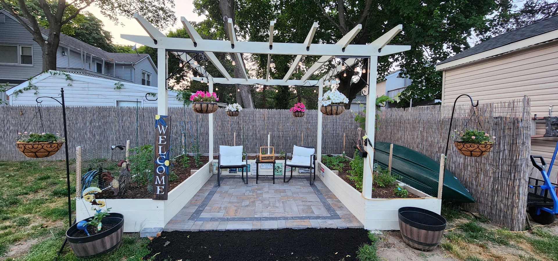There is a pergola in the backyard with a table and chairs underneath it.