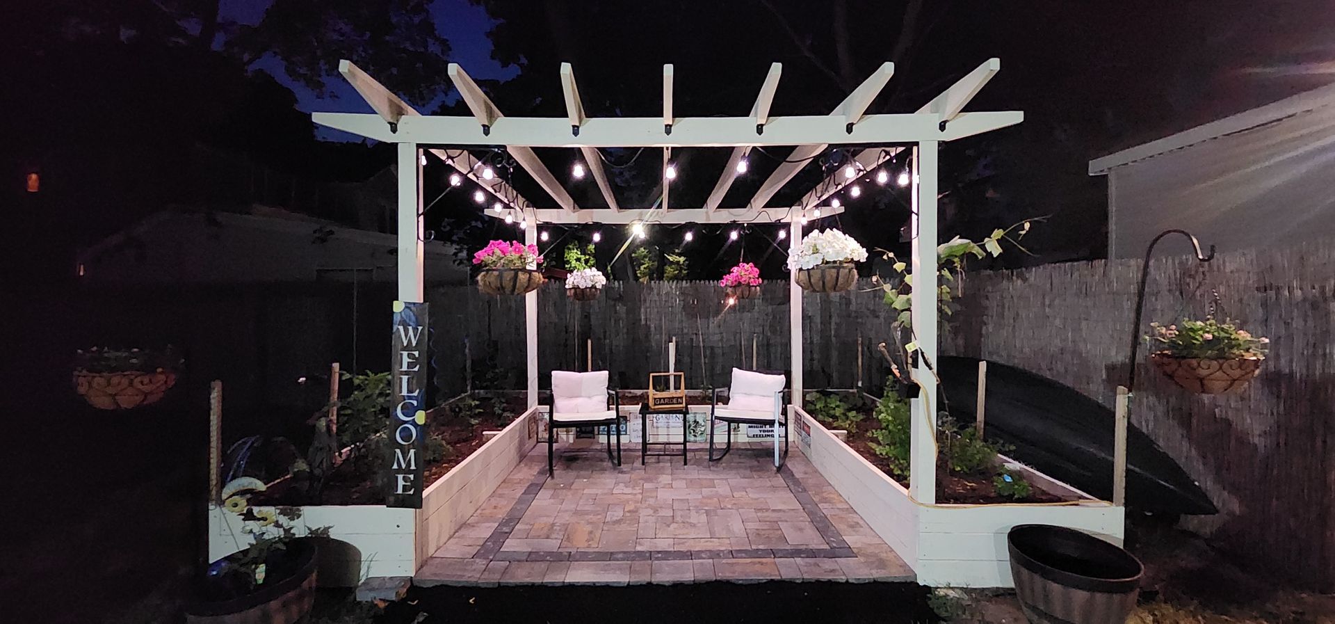 A pergola with a table and chairs underneath it is lit up at night.