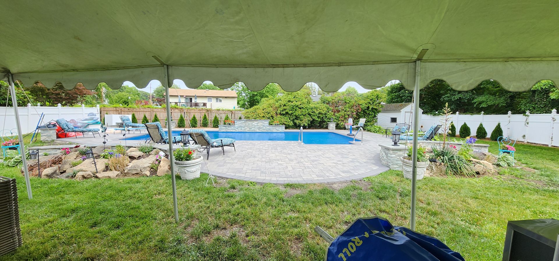 A view of a backyard with a pool from under a tent.