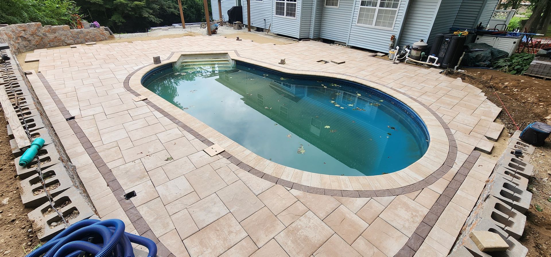 A swimming pool is being built in the backyard of a house.
