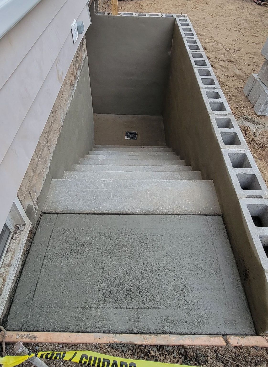 A concrete staircase is being built in the backyard of a house