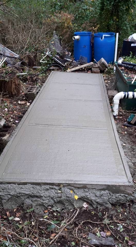 A concrete walkway is being built in a backyard.