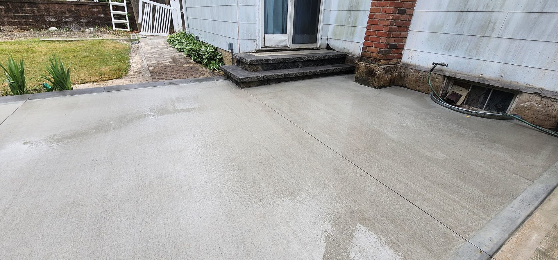 A concrete driveway in front of a house with steps leading to the door.