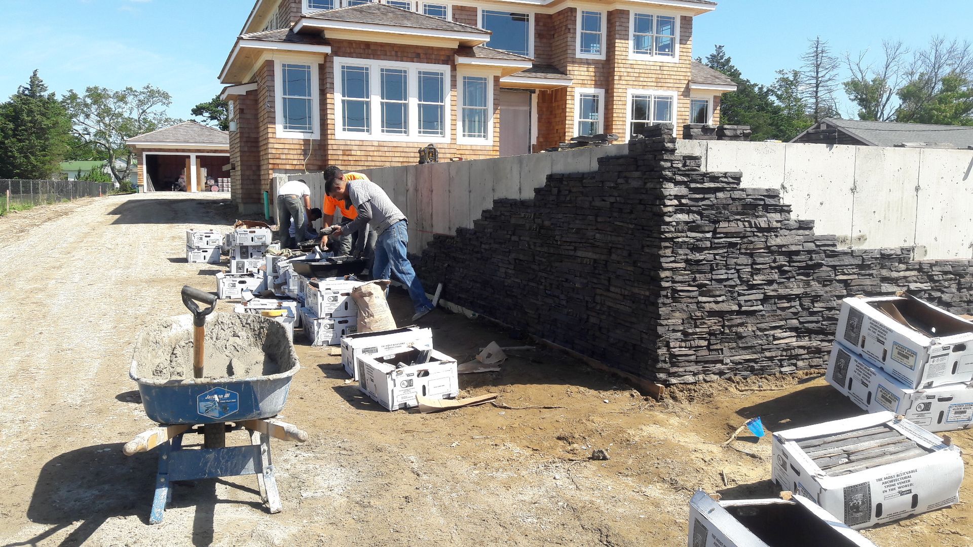 A large house is being built and a wheelbarrow is in front of it
