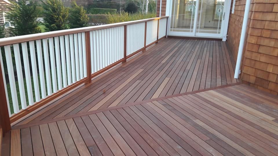A wooden deck with a white railing and sliding glass doors