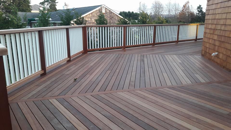 A wooden deck with a white railing and a house in the background