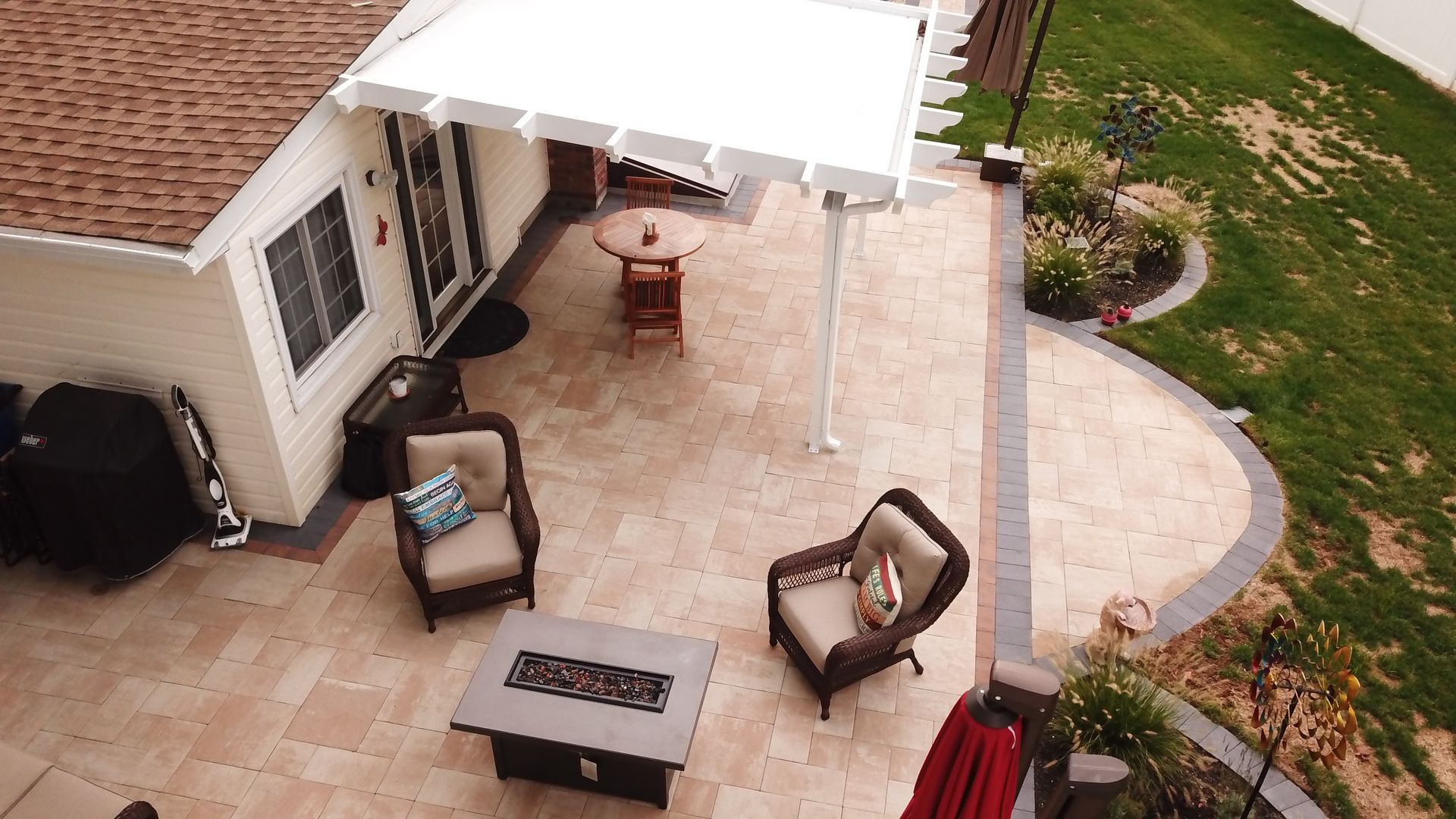 An aerial view of a patio with chairs , a table and a fire pit.