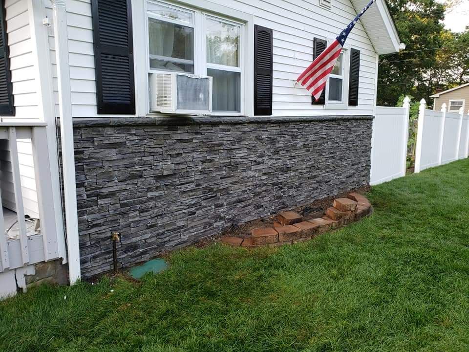 A house with a stone wall and an american flag on the side of it.