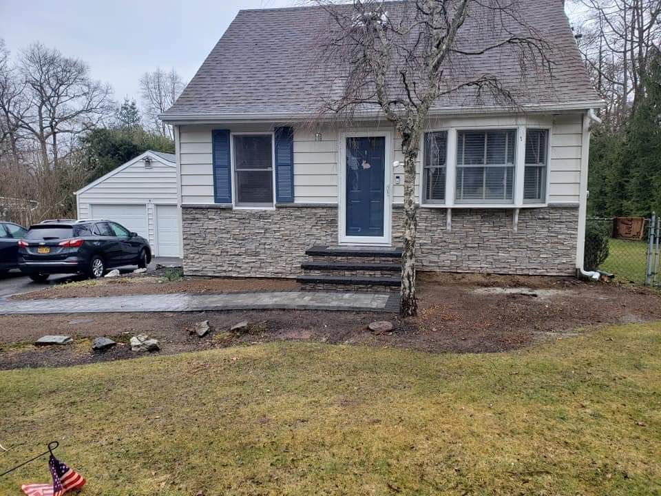 A white house with a blue door is sitting in the middle of a grassy field.